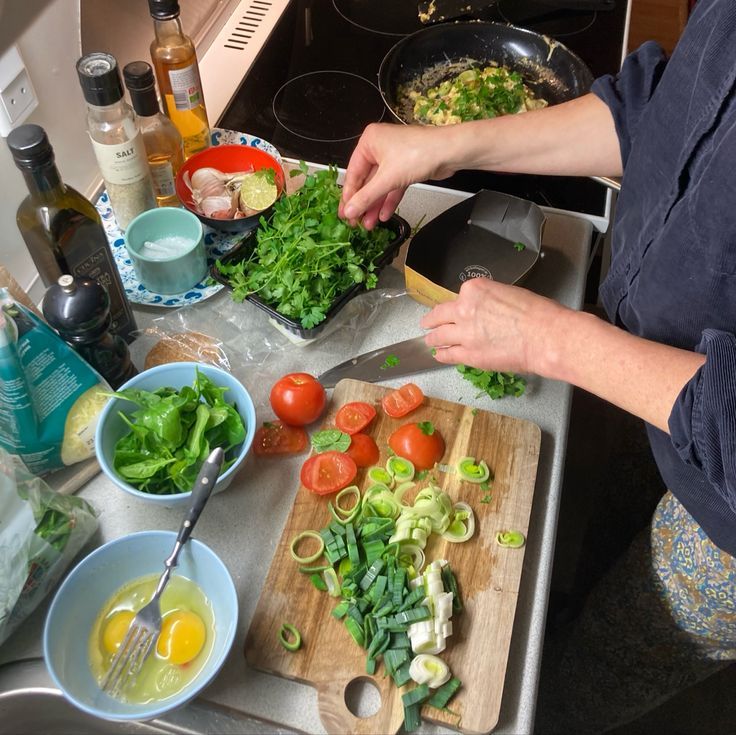 Wooden kitchen table arranged with fresh seasonal vegetables, grains, and a notebook